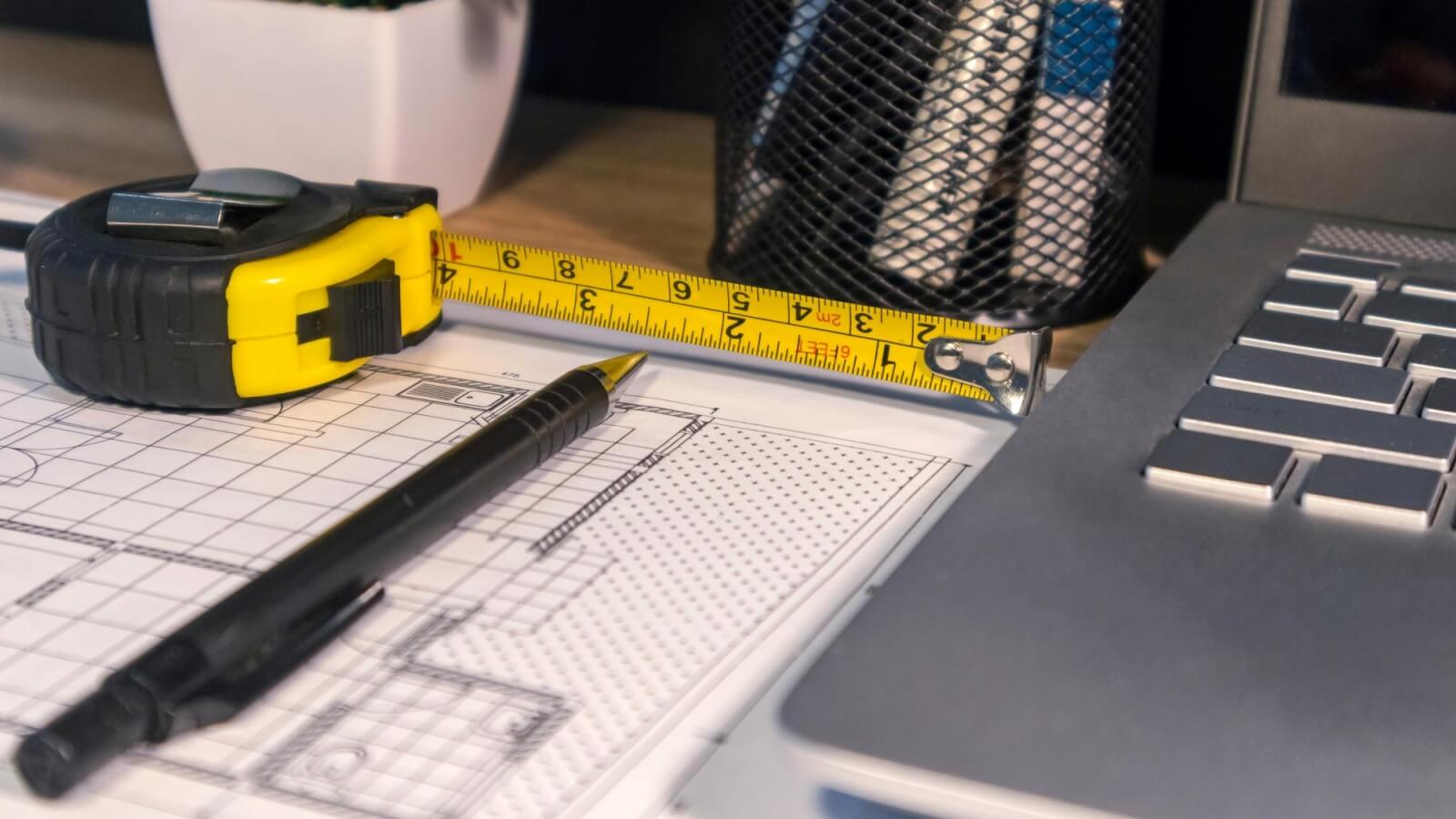 Estimator measuring a wall dimension on a set of construction blueprints during a blueprint takeoff